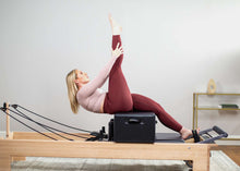 Load image into Gallery viewer, padded footstrap for reformer exercises in use | caption::Medium Footstrap on Studio Reformer with Revo Footbar