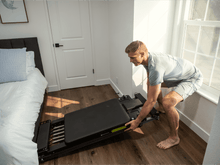 Load image into Gallery viewer, A man is storing a Metro-IQ Pilates Reformer.