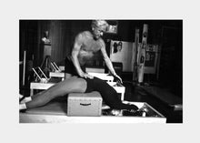 Load image into Gallery viewer, Vintage photograph of a student guided by Joseph Pilates on a sitting box and reformer. | caption::Short Box