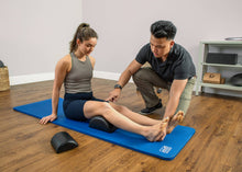 Load image into Gallery viewer, Instructor helping a student to correctly position a half-cylinder cushion for maximum benefit.