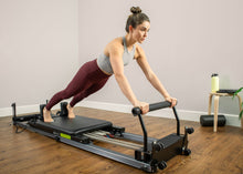 Load image into Gallery viewer, Woman using a Metro IQ Pilates Reformer.