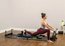 Load image into Gallery viewer, Female practitioner using Metro IQ Pilates Reformer machine for a Pilates workout session.
