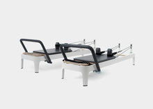 Load image into Gallery viewer, A photo of the Allegro 2 Pilates Reformer with legs showing both the carbon fiber footbar and the steel footbar options. | caption::Carbon Fiber Footbar (left), Steel Footbar (right)
