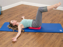 Load image into Gallery viewer, Woman lying on red inflatable wedge on blue mat.
