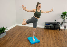 Load image into Gallery viewer, Woman balancing on one leg on a blue balance pad.
